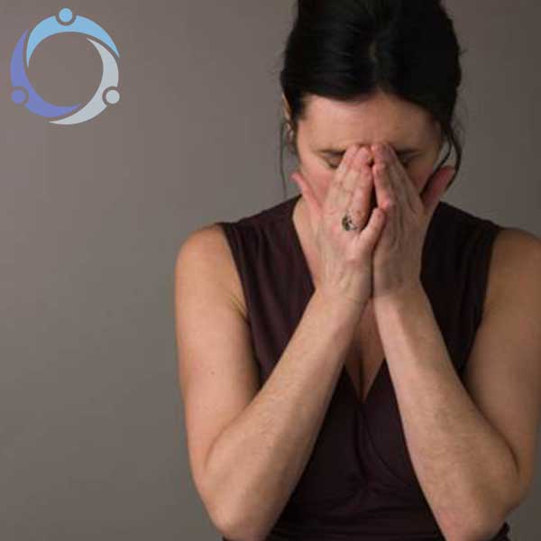 A woman covers her face as she stresses over how to help someone with PTSD.