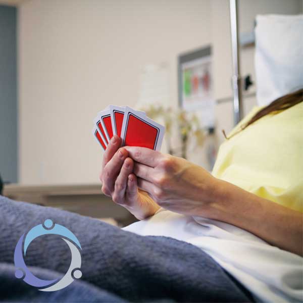 A woman plays cards in her hospital bed as a way to help with brain injury recovery.