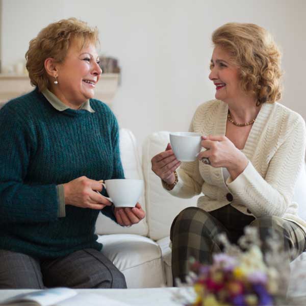 Two women talk about setting up a care calendar over coffee.