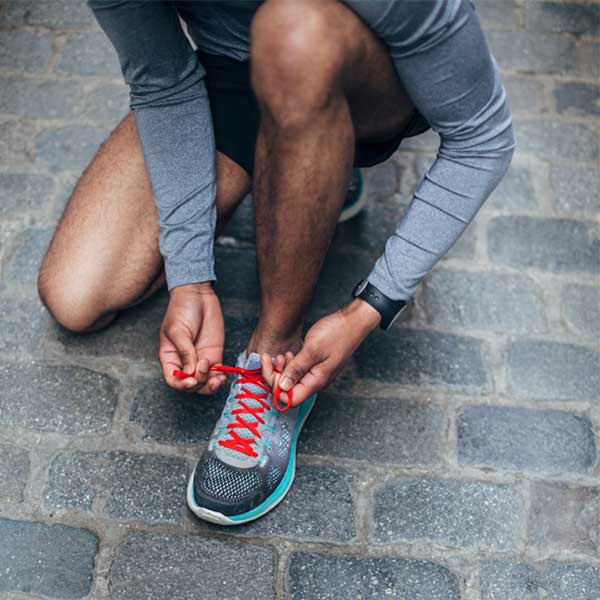 As a man ties his gym shoes, he wonders if it's healthy to exercise while sick.