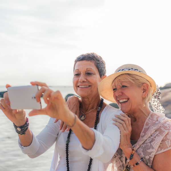 One woman shows another how to help take a selfie photo.