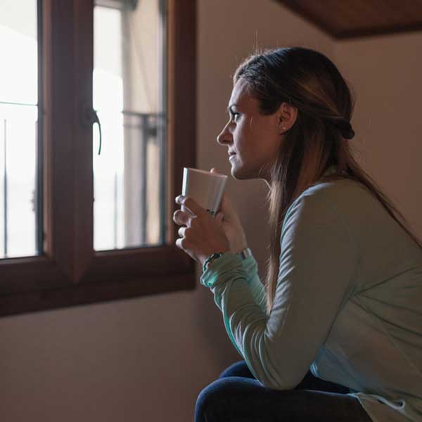 A woman sips her coffee while thinking of ways to support her spouse living with cancer.