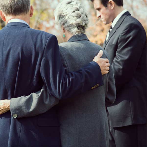 A son comforts his mother while planning a funeral.