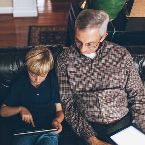 A grandfather and grandson practice internet safety while surfing the web on their tablets.