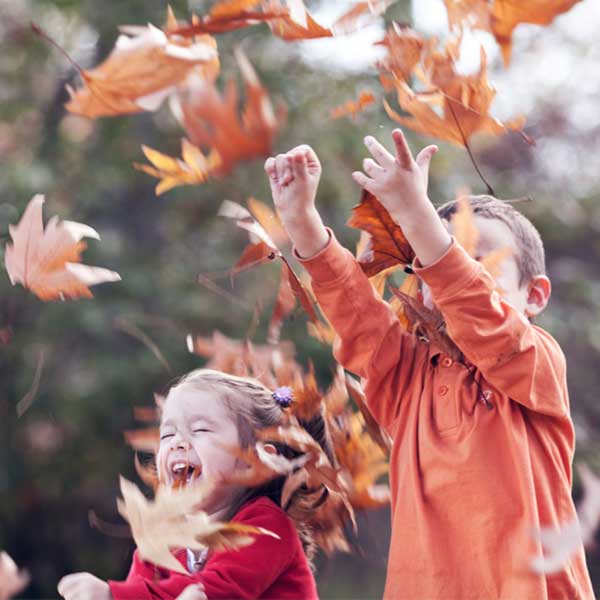 Two children play with leaves, which is a fun way to be working with disabled children.