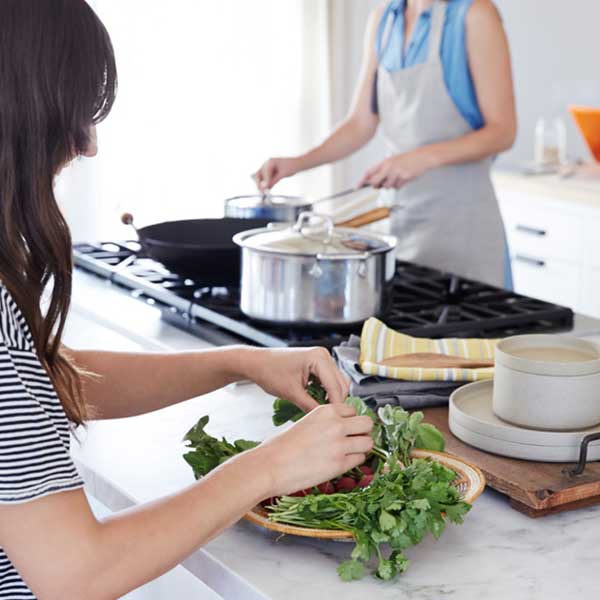 A woman preps her meal with a friend in order to learn how to save time in the kitchen.